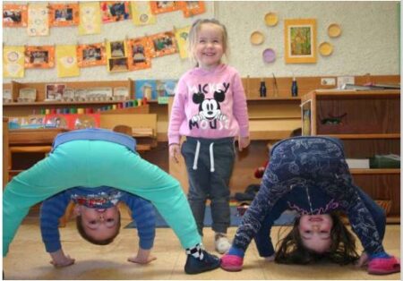 Das Foto zeigt drei Kinder, wovon zwei kopf&uuml;ber in die Kamera schauen